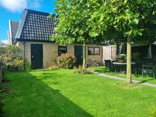 une cour avec une maison et une pelouse avec un arbre dans l'établissement Klein Middelweg, à Uitgeest