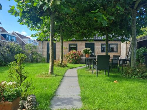 a garden with a table and chairs in the grass at Klein Middelweg in Uitgeest