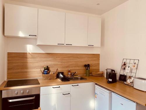 uma cozinha com armários brancos e um lavatório em Cosy Studio - Verneuil d'Avre et d'Iton em Verneuil d’Avre et d’Iton