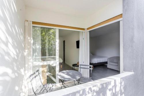 een kamer met een balkon met een stoel en een bed bij Le Roucas - Chaleureux appartement aux Baux de Provence in Les Baux-de-Provence