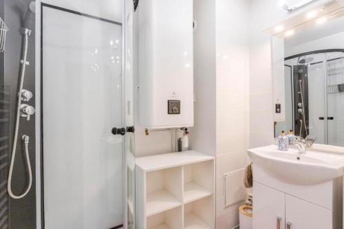 La salle de bains blanche est pourvue d'un lavabo et d'une douche. dans l'établissement Le Roucas - Chaleureux appartement aux Baux de Provence, aux Baux-de-Provence