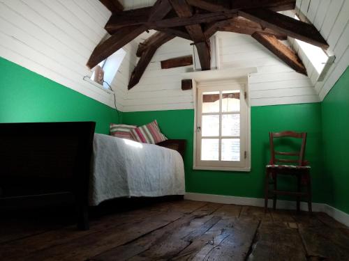 - une chambre avec des murs verts, un lit et une fenêtre dans l'établissement Maison en plein cœur de ville à Montmorillon, à Montmorillon