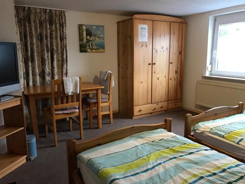 a bedroom with two beds and a desk and a television at Pension Grüner Baum 