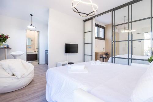 1 dormitorio blanco con 1 cama blanca grande y TV en Central chic flat with terrace btw Syntagma & Monastiraki en Athens