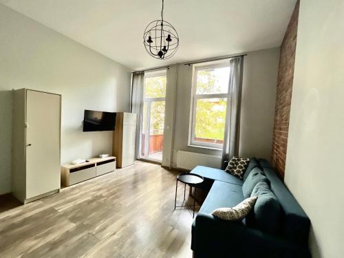 a living room with a blue couch and a television at The Garbary - parking free in Bydgoszcz