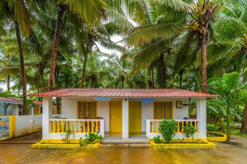 a small house with palm trees in the background at Whoopers Party Hostel, Palolem in Palolem