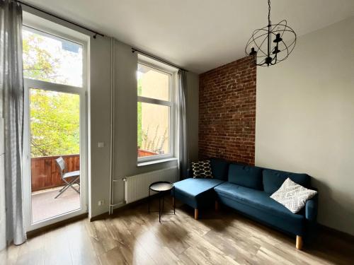 a living room with a blue couch and a brick wall at ACM Centrum Apartament z parkingiem in Bydgoszcz