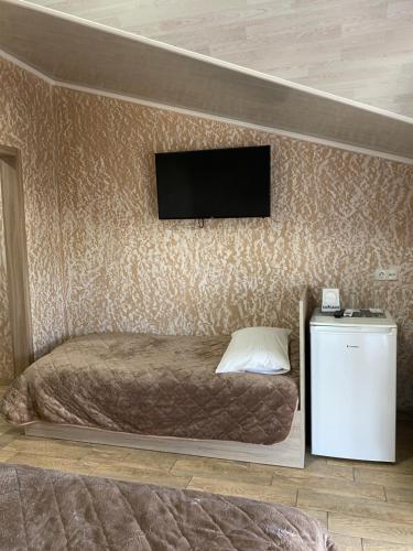 a bedroom with a bed and a television on a wall at Hotel Chicago in Umanʼ