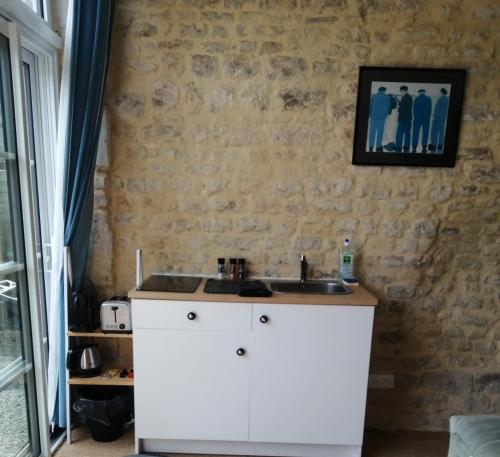 une cuisine avec un évier et un mur en pierre dans l'établissement Studio Vargas avec jardin - Omaha Beach, à Colleville-sur-Mer