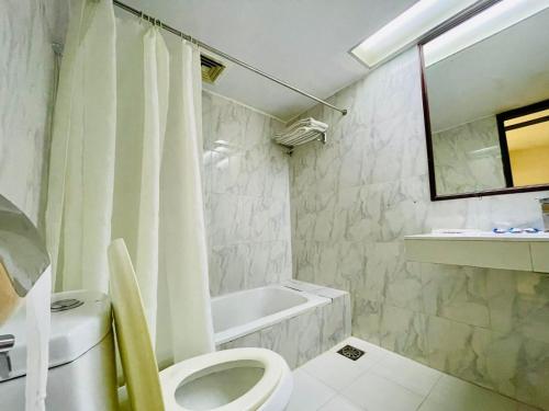 a bathroom with a toilet and a tub and a sink at Orchid Business Hotel in Chittagong