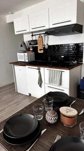 une cuisine avec des placards blancs et des plaques noires sur une table dans l'établissement Appartement T1bis Saint Herblain, à Saint-Herblain