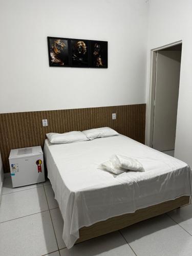 um quarto com uma cama grande e lençóis brancos em Casa com piscina Capitólio em Capitólio