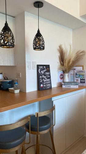 a kitchen with two bar stools at a counter at LeisureStay Studio @ Azure North in San Fernando