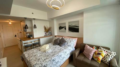 1 dormitorio con cama, sofá y escritorio en LeisureStay Studio @ Azure North en San Fernando