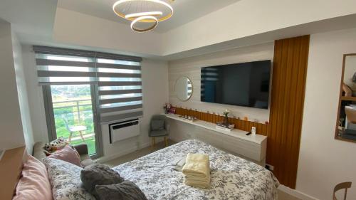 a bedroom with a bed and a tv and a window at LeisureStay Studio @ Azure North in San Fernando