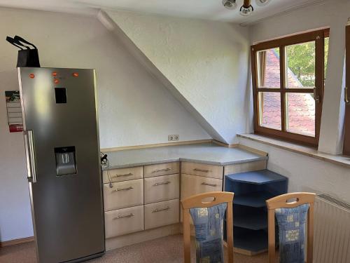 uma cozinha com um frigorífico, uma mesa e 2 cadeiras em FeWo im Gasthof Forsthaus em Marktredwitz