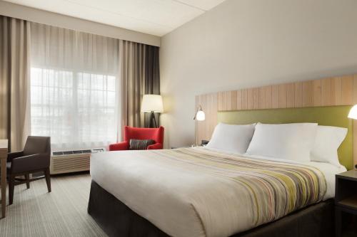 Cette chambre comprend un grand lit et une chaise. dans l'établissement Country Inn & Suites by Radisson, Jackson, TN, à Jackson