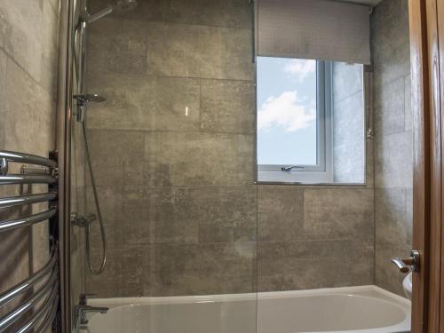 a bathroom with a shower and a tub and a window at Gable End Cottage in Ingleton