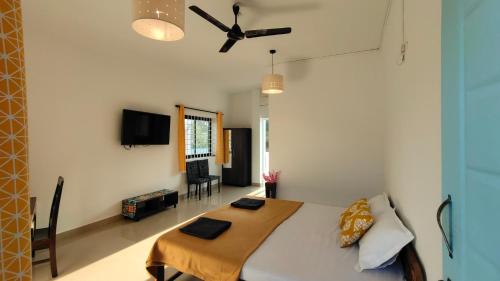 een slaapkamer met een bed en een plafondventilator bij Iksa in Mandrem
