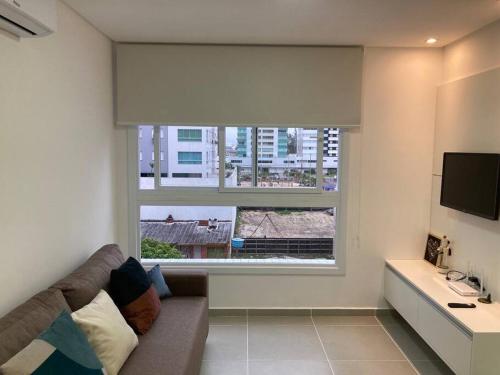 a living room with a couch and a large window at Apartamento a 100m da beira-mar in Capão da Canoa