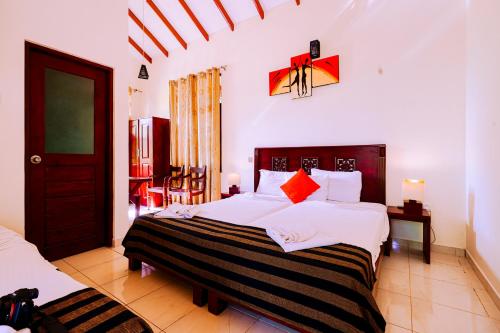 a bedroom with two beds with white sheets and red pillows at Safari Lodge Yala in Kataragama