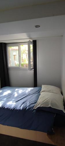 una camera con un letto blu e una finestra di Chambre privée bien desservie par les transports en commun a Colombes