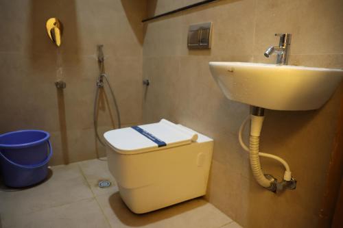 a bathroom with a toilet and a sink at Hotel Amoha in Palani
