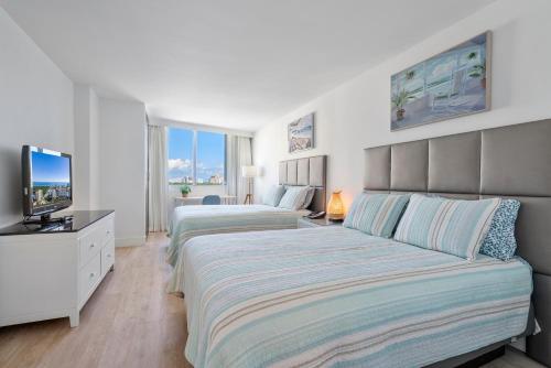 a bedroom with two beds and a television in it at Beach Apartments by Avi Real Estate in Fort Lauderdale