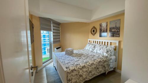 a small bedroom with a bed and a window at Two Bedroom - The Bali Corner at Azure North in San Fernando