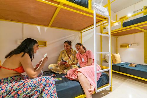 three women are sitting in a bunk bed at Whoopers Party Hostel, Palolem in Palolem