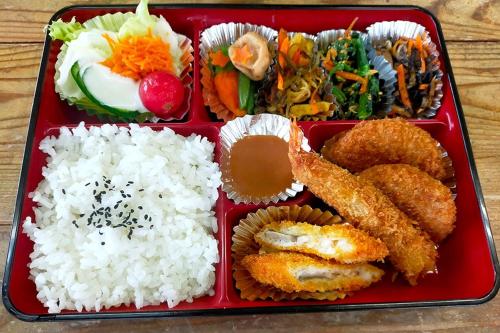 una bandeja roja de comida con arroz y diferentes alimentos en 民宿 和合 Minshuku WAGO en Tanabe