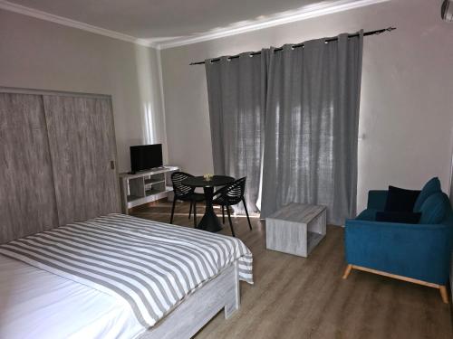 a bedroom with a bed and a chair and a table at Beachfront Coziness in Flic-en-Flac