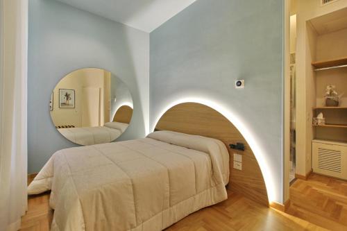 - une chambre avec un lit et un miroir circulaire dans l'établissement Dea Rome Suites, à Rome