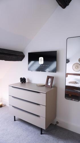 a dresser with a tv on a white wall at Wild Drive Chester - Stunning cottage just minutes from Chester and Zoo in Chester