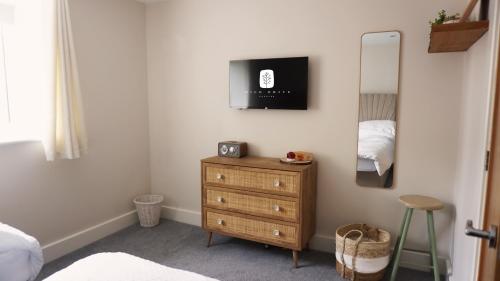 a bedroom with a dresser and a tv on the wall at Wild Drive Chester - Stunning cottage just minutes from Chester and Zoo in Chester