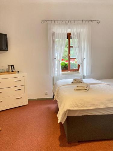 a bedroom with a bed and a dresser and a window at Penzion Moravia - free parking in the city center in Mikulov