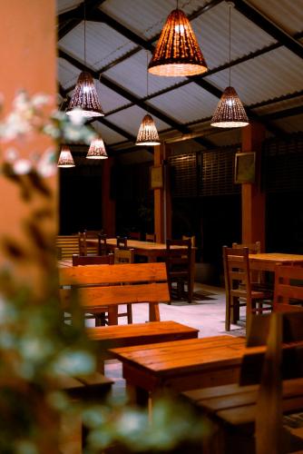 a restaurant with wooden tables and chairs and lights at Safari Lodge Yala in Kataragama