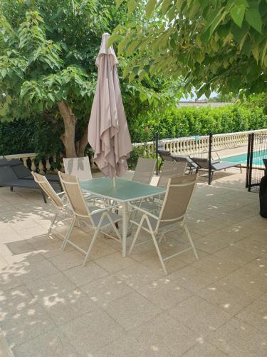 mesa y sillas con sombrilla y piscina en Villa Gesinacris avec piscine, en Camaret-sur-Aigues