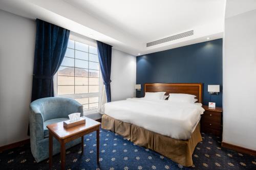 فندق ايديل هوم Ideal home hotel في المدينة المنورة: غرفه فندقيه بسرير وكرسي ونافذه