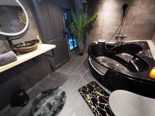 a bathroom with a black tub and a sink at Cosy Loft near Geneva with Wi-Fi and Netflix in Ornex
