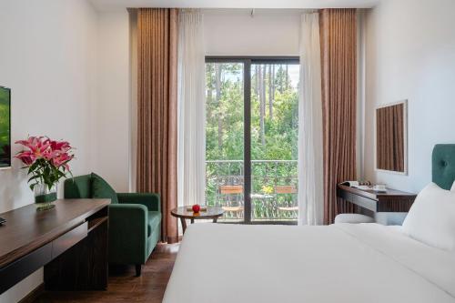 een hotelkamer met een bed, een bureau en een raam bij TTR Moonstone Apart Hotel in Da Lat