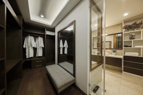 ein Bad mit einem begehbaren Kleiderschrank mit weißen Hemden und einem Spiegel in der Unterkunft Hanoi Premium 160 Sqm Apt with Top-Quality Furnishing in Hanoi