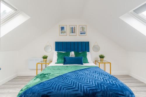 a white bedroom with a blue bed and two tables at Cardiff Luxe Living Apartments in Cardiff