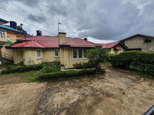 a house with a red roof on a dirt road at Ruchi House in Nuwara Eliya