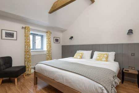 1 dormitorio con 1 cama grande y 1 silla en Gilliflower 1 bedroom cottage at Trethwale Barns Holiday Home en Saint Keyne