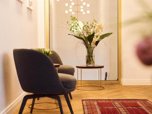two chairs and a vase of flowers in a room at Hotel Lindenufer in Berlin