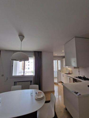 a kitchen and living room with a white table and chairs at CityCosy Super Moderne, Confortable, Spacieux et Calme in La Marsa