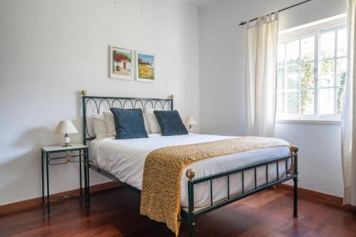 Un dormitorio con una cama con almohadas azules y una ventana en Casa da Hera, en Ericeira