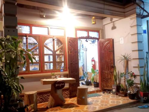 a room with a table and some plants and windows at Khamphouy Guesthouse in Champasak