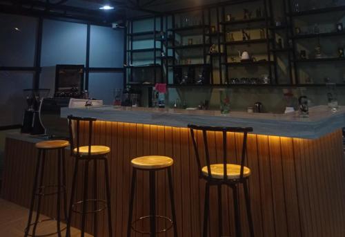a bar with four bar stools in a room at T HOTEL KUALANAMU in Lubukpakam